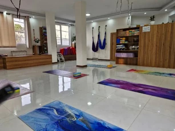 سالن تمرین استودیو با مت های رنگی و پنجره‌های بزرگ